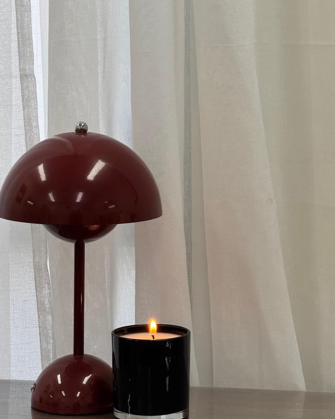 An oxblood lamp and a lit candle in the studio.